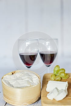 Two glasses of red wine and cheese board on wooden tray - vertical.