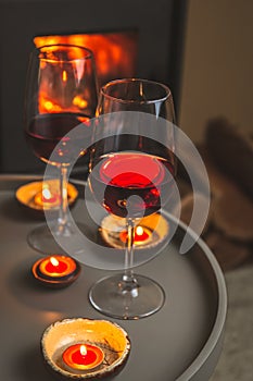 Two glasses of red wine front of fireplace. Romantic light