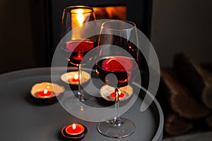 Two glasses of red wine front of fireplace. Romantic light