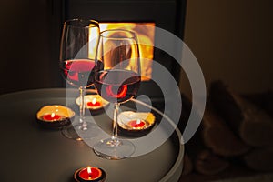 Two glasses of red wine front of fireplace. Romantic light