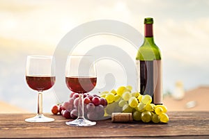 Two glasses of red wine, grape, bottle on wooden table