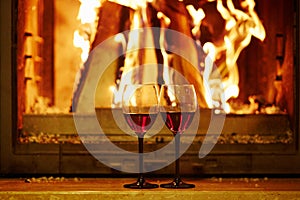 Two glasses of red wine near fireplace