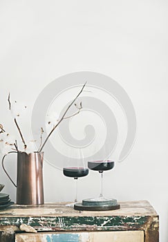 Two glasses of red wine over rustic kitchen countertop