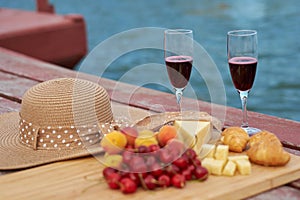 Two glasses of red wine, served outdoor with fruits and beautiful blue ocean view.