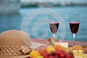 Two glasses of red wine, served outdoor with fruits and beautiful blue ocean view.