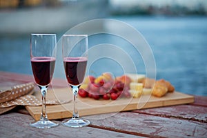 Two glasses of red wine, served outdoor with fruits and beautiful blue ocean view.