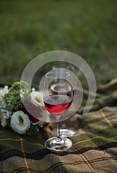 Two glasses of red wine stand on a checkered plaid