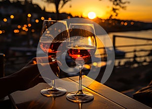 Two glasses of red wine are on the table in the restaurant on the background of the sea and the sunset