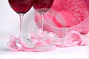 Two glasses of red wine on a white background near pink panties photo