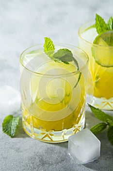 Two glasses of refreshing drinks with ice cubes, juice and lime fruit, party cocktail