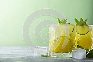 Two glasses of refreshing drinks with ice cubes, juice and lime fruit, party cocktail. Copy space