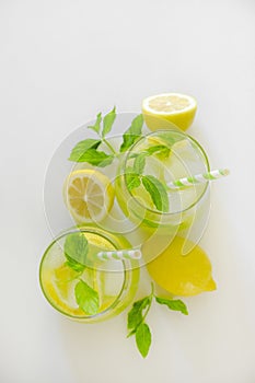 Two glasses of refreshing non alcoholic mojito drink with lemon slices, mint leaves and ice. Studio shot of iced lemonade isolated