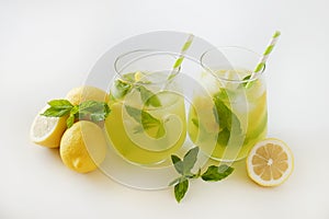 Two glasses of refreshing non alcoholic mojito drink with lemon slices, mint leaves and ice. Studio shot of iced lemonade isolated