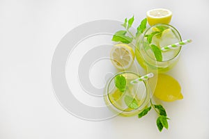 Two glasses of refreshing non alcoholic mojito drink with lemon slices, mint leaves and ice. Studio shot of iced lemonade isolated