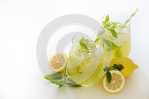 Two glasses of refreshing non alcoholic mojito drink with lemon slices, mint leaves and ice. Studio shot of iced lemonade isolated