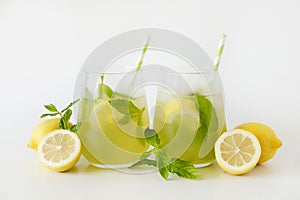 Two glasses of refreshing non alcoholic mojito drink with lemon slices, mint leaves and ice. Studio shot of iced lemonade isolated