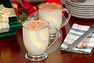 Two glasses of rich eggnog in a holiday table setting