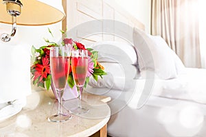 Two glasses of rose champagne with light festive bokeh in the upscale hotel room. Dating, romance, honeymoon, valentine