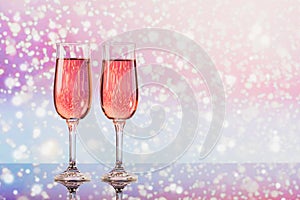 Two glasses of rose champagne with a light snow bokeh as a background. Romantic dinner. Winter, Christmas or New Year