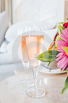 Two glasses of rose champagne in the upscale hotel room. Dating, romance, honeymoon, valentine, getaway concepts