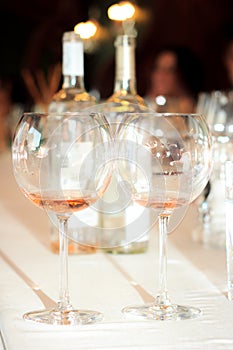 Two glasses with rose wine on the background of two wine bottles in a restaurant