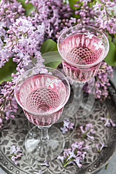 Two glasses of rose wine and  lilac bouquet, selective focus
