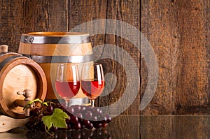 Two glasses of rosÃ© wine with two barrels and grapes