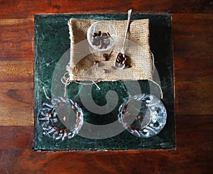 Two glasses of sambuca, italian liqueur, with coffee beans on a green marble surface lying on a wooden table