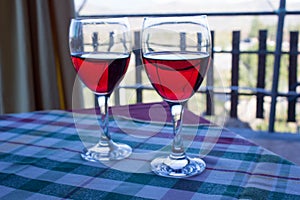 Two glasses of Sicilian red wine on the table covered with checkered tablecloth