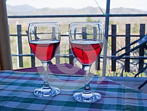 Two glasses of Sicilian red wine on the table covered with checkered tablecloth