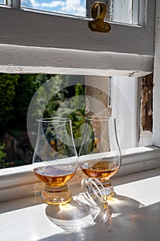 Two glasses of single malt scotch whisky served on old window sill in Scottisch house with view on old part of Edinburgh, Scotland