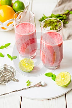 Two Glasses of Smoothie with Berries, Grapefruit, Lemon, Lime and Mint on White Wooden Background, Detox Time