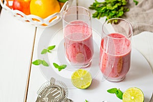 Two Glasses of Smoothie with Berries, Grapefruit, Lemon, Lime and Mint on White Wooden Background, Detox Time