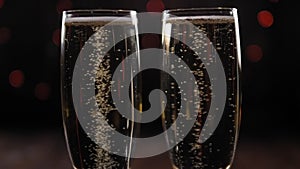 Two glasses of sparkling wine on a black background with blurred flashing lights