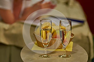 Two glasses of sparkling wine in hotel room with woman in background