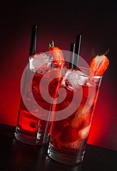 Two glasses of strawberry cocktail with ice on wood table