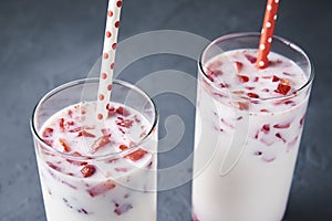 Two glasses with strawberry milk smoothie on a dark background