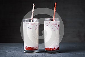 Two glasses with strawberry milk smoothie on a dark background