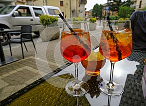 Two glasses of summer cocktail on the table across fried potatoes and city street. Aperitif time. Summertime relax