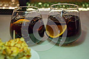 Two glasses of Vermouth or Martini with orange slice, tortilla appetizer
