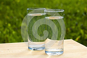 Two glasses of water on grass background photo