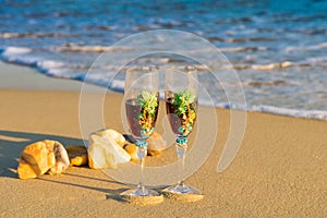 Two glasses in a wave of the sea on the beach