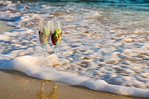 Two glasses in a wave of the sea on the beach