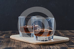 Two Glasses of whiskey with ice cubes on a wooden table/Two Glasses of whiskey with ice cubes on a wooden table. Black background