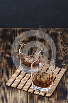 Two Glasses of whiskey with ice cubes on a wooden table/Two Glasses of whiskey with ice cubes on a wooden table. Black background