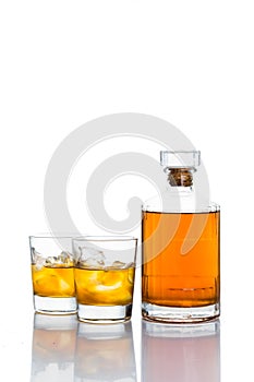 Two glasses of whiskey on the rocks, with a whiskey bottle in white background