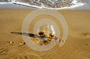 two glasses of whiskey single malt on the sand washed by the waves, a glass of tasting, relax on the beach