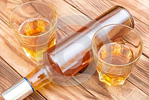 Two glasses of whisky with bottle of whiskey on wooden background