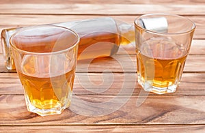 Two glasses of whisky with bottle of whiskey on wooden background