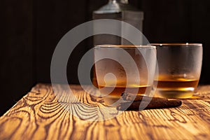 Two glasses of whisky and cigars on wooden table